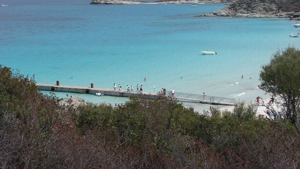 A coastal view with a pier, clear turquoise water, and rocky hills in the background. - comfortable rental type f2 in the heart of the vineyard with swimming pool  (Patrimonio)