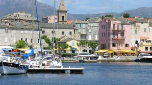 A coastal town with colorful buildings, a prominent church tower, and boats docked at the harbor. - comfortable rental type f2 in the heart of the vineyard with swimming pool  (Patrimonio)
