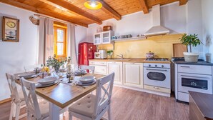 Una cocina acogedora con vigas de madera, una mesa de comedor dispuesta para cuatro personas y electrodomésticos modernos.
