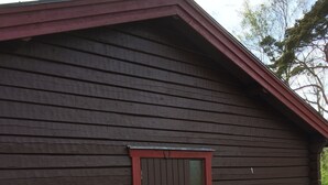 A wooden building with a dark brown exterior and a red-framed door. - Fantastic family vacation 600m from sandy beach, large garden, near forest, river (Mellbystrand)