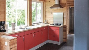 A compact kitchen with red cabinets, a gas stove, and a window overlooking greenery. - Beautiful home in Wijdenes with house sea view (Wijdenes)