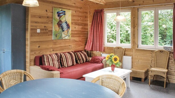 A cozy cabin interior with a red sofa, wicker chairs, a white table, and a painting on the wall. - Beautiful home in Wijdenes with house sea view (Wijdenes)