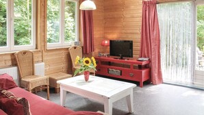 A cozy room with a white table, wicker chairs, a red entertainment unit, and a TV. - Beautiful home in Wijdenes with house sea view (Wijdenes)