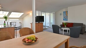 A modern living room with a dining area, a TV, and a balcony with a view. - 6 pers. Apartment 13 Villa Celia Sellin - Villa Celia Sellin (Sellin)