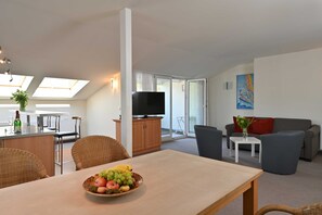 Ein modernes Wohnzimmer mit Essbereich, Fernseher und Balkon mit Blick.