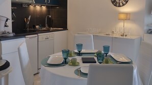 A modern kitchen with dark blue cabinets, a white countertop, and a round dining table set with blue glassware. - Sleeps 4. On the beach front with sea view, at 20 m from the beach, wi (Fréjus)