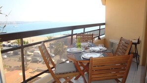 A balcony with a table set for two, overlooking a beach and parking area. - Sleeps 4. On the beach front with sea view, at 20 m from the beach, wi (Fréjus)