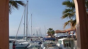 A marina with boats docked, a person walking, and palm trees in the background. - Sleeps 4. On the beach front with sea view, at 20 m from the beach, wi (Fréjus)