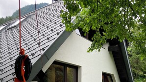 A modern house with a sloped roof, large windows, and a wooden deck.