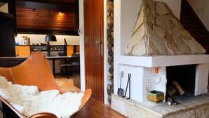 A cozy living room with a stone fireplace, a fluffy white rug, and a wooden dining table.