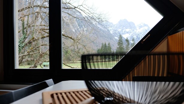 A room with a view of mountains through a skylight, a wooden cutting board, and a black bowl.