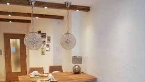 A dining area with a wooden table, chairs, and two hanging crystal chandeliers. - Completely renovated and newly designed apartment (Kirchberg in Tirol)