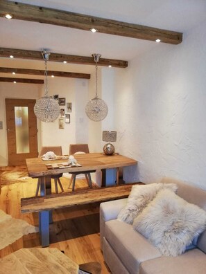 A dining area with a wooden table, chairs, and two hanging crystal chandeliers. - Completely renovated and newly designed apartment (Kirchberg in Tirol)