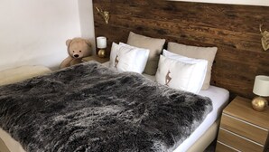 A bed with a dark furry blanket, a wooden headboard, and multiple pillows. - Completely renovated and newly designed apartment (Kirchberg in Tirol)