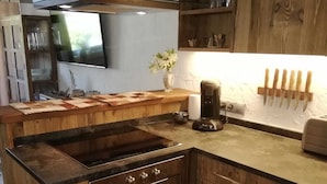 A kitchen with wooden cabinetry, a built-in stove, and a coffee maker. - Completely renovated and newly designed apartment (Kirchberg in Tirol)