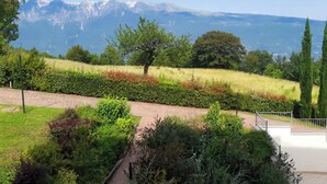 Un jardin aménagé avec un sentier, un arbre et une vue sur des montagnes lointaines.