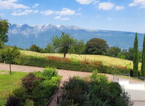 A landscaped garden with a pathway, a tree, and a view of distant mountains.
