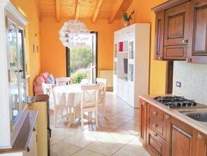 A kitchen with a dining area, wooden cabinets, a gas stove, and a view through the open door.