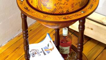 Una mesa con forma de globo de madera, con una botella de ginebra y vasos para chupitos debajo.