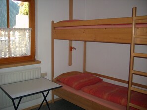 Ein Stockbett mit Tisch und Fenster mit Bergblick.