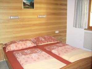 A double bed with floral bedding, a wooden headboard, a nightstand, and a wall-mounted picture. - Rotenkogel - Gratzhof - Kals (Lesach)