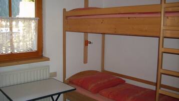 Ein Stockbett mit Schreibtisch und Fenster mit Spitzenvorhängen.