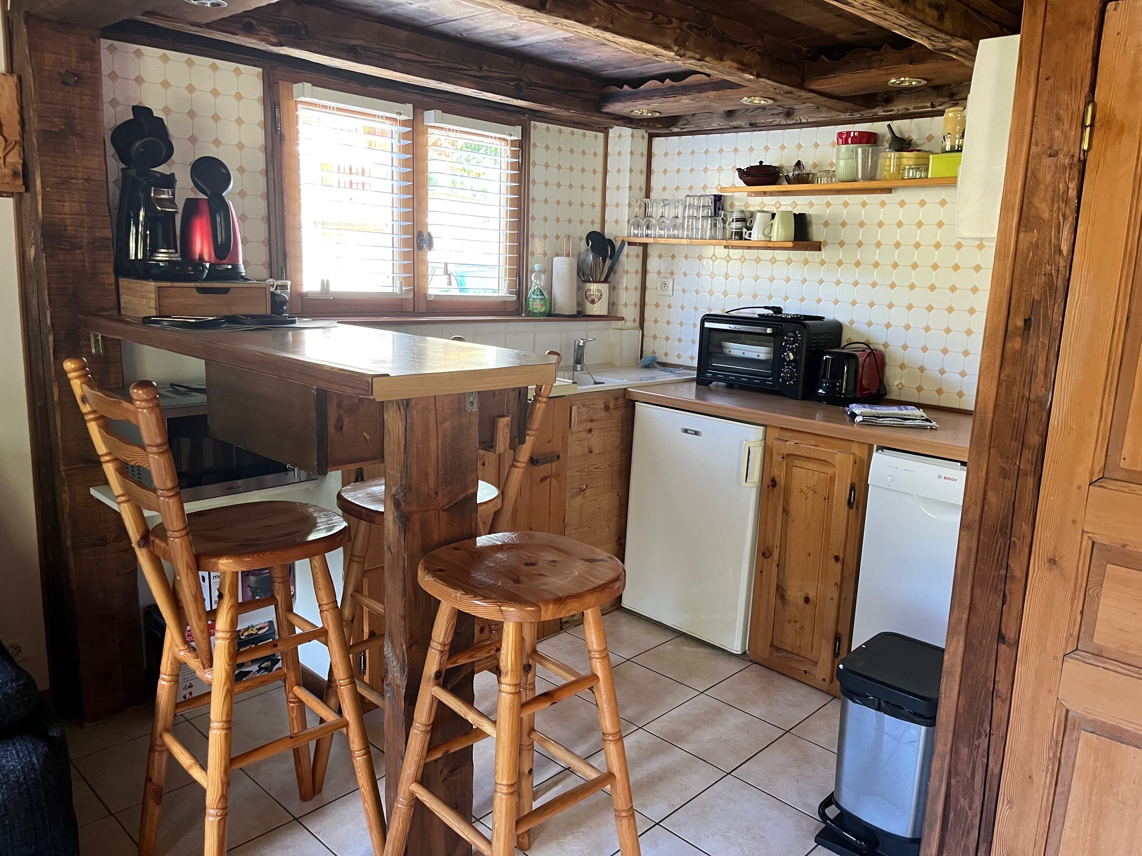 Une cuisine équipée de tabourets en bois, d’une machine à café, d’un grille-pain et d’un lave-vaisselle Bosch.
