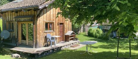 A rustic wooden cabin with a patio, a small table, and chairs.
