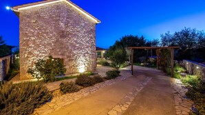 Un edificio de piedra con un sendero empedrado que conduce a una pérgola de madera.