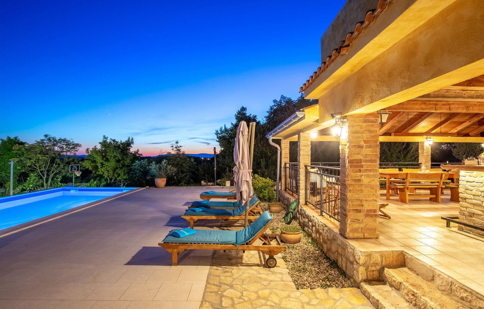 Ein Poolbereich mit Liegestühlen und einer überdachten Terrasse mit Sitzgelegenheiten.