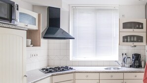 A kitchen with white cabinets, a black range hood, a window with blinds, and a coffee maker. - Amazing home in Winterswijk with WiFi (Winterswijk)