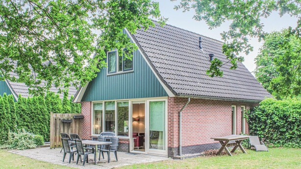 A house with a brick exterior, a green roof, and a patio with outdoor furniture. - Amazing home in Winterswijk with WiFi (Winterswijk)