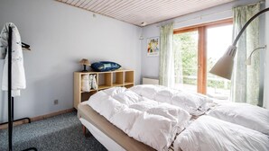 A bedroom with a bed, a wooden shelf with pillows, a lamp, and a window with curtains. - Cozy home in Ejstrupholm with kitchen (Ejstrupholm)