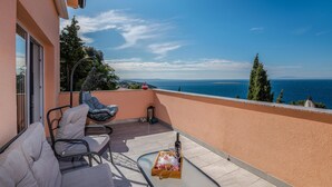A balcony with a view of the sea, a table with a bottle and glasses, and two chairs. - 1 bedroom awesome apartment in Stara Baska (Stara Baska)