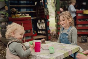 A child playing with a toy at a table with a patterned tablecloth. - Groat Fleet **** - Groat Fleet (Neuenkirchen)