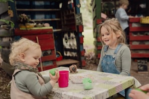 Un enfant joue avec un jouet à une table recouverte d’une nappe à motifs.