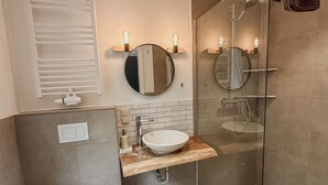 A modern bathroom with a glass shower enclosure, a round mirror, a sink with a wooden countertop, and a toilet. - Groat Fleet **** - Groat Fleet (Neuenkirchen)