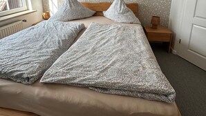 A bedroom with a bed, a bedside table with a lamp, a window, and a door. - Groat Fleet **** - Groat Fleet (Neuenkirchen)