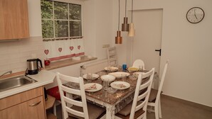 A kitchen with white cabinets, a window, a sink, a coffee maker, and a dining table set with plates and glasses. - Groat Fleet **** - Groat Fleet (Neuenkirchen)