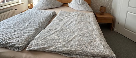 A bedroom with a bed, a bedside table with a lamp, a window, and a door.