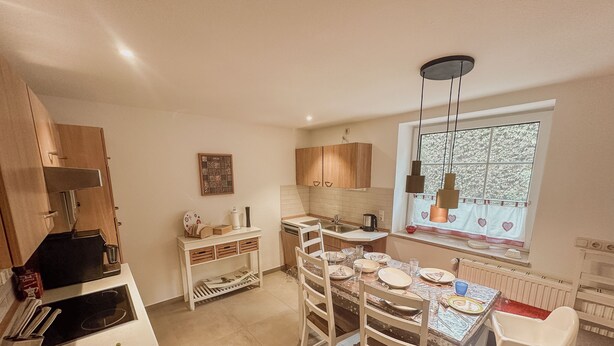A kitchen with a dining table, chairs, a fruit bowl, and a window with curtains. - Groat Fleet **** - Groat Fleet (Neuenkirchen)