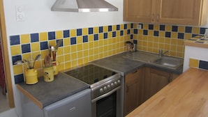 A compact kitchen with a gas stove, oven, and a stainless steel range hood.