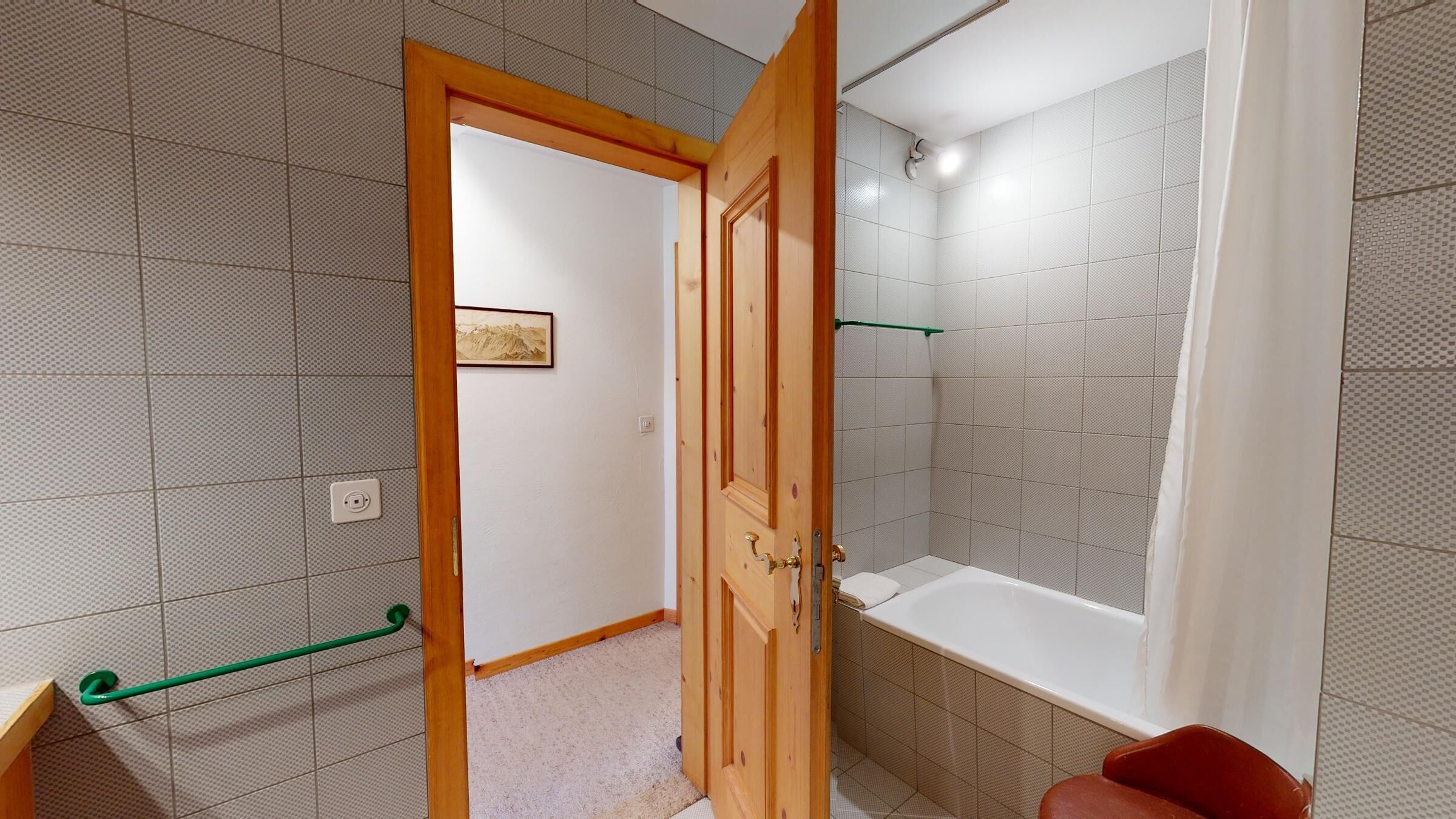 A bathroom with a bathtub, a shower, and a door leading to another room.