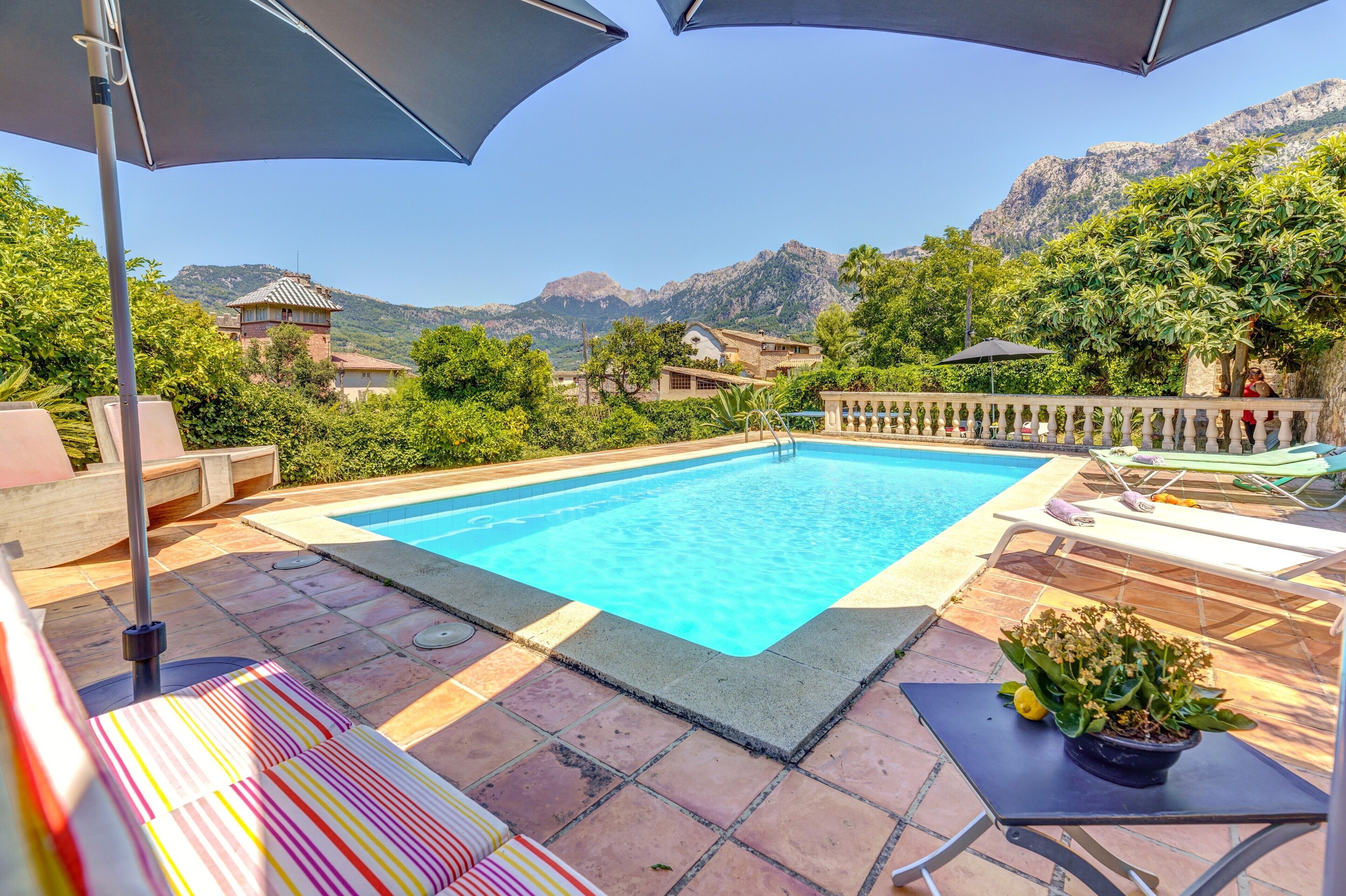 Ein Schwimmbecken mit Bergblick, Sitzgelegenheiten im Freien und einem Blumentopf.
