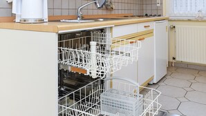 Une cuisine moderne équipée d’un lave-vaisselle intégré, d’une machine à café et d’un four à micro-ondes.