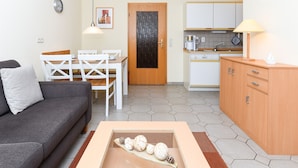 Un espace de vie compact comprenant un canapé, une table à manger et un coin cuisine.