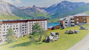 A modern hotel with multiple buildings, a large lake, and mountains in the background. - 3-room apartment, 8 people, ski-in, near shops in Tignes (Tignes)