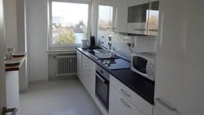 Una cocina moderna con armarios blancos, encimera negra, microondas y una ventana con vistas al exterior.