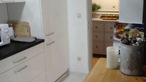 Cocina compacta con alacenas blancas, microondas y encimera de madera.