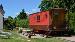 A red wooden cabin with a balcony, a picnic table, and a hammock in a garden setting. - Unusual gite equipped to receive up to 5 people (Seux)